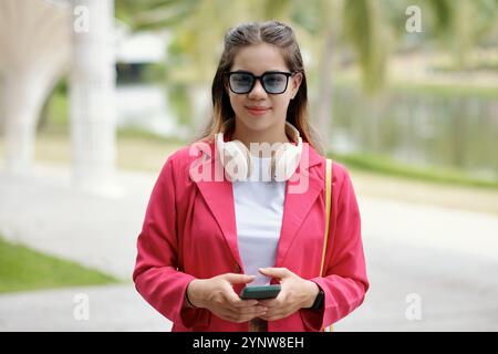 Smiling Woman Wearing Sunglasses and Holding Smartphone Stock Photo