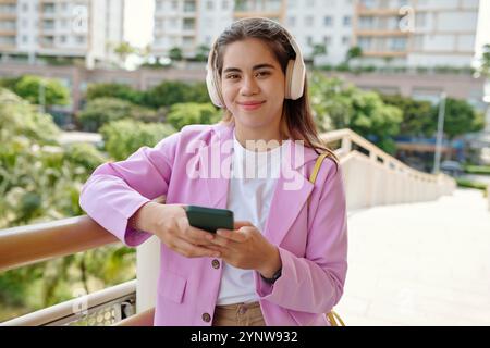 Smiling Young Woman Listening Music with Headphones Outdoors Stock Photo