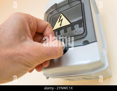 A man's hand opens the lid of a box with electrical automatic safety switches (circuit breakers). Stock Photo