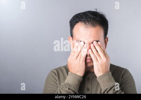 A man covers his eyes with both hands, symbolizing the vision complications from diabetes, known as diabetic retinopathy. Highlights the importance of Stock Photo