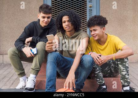 teen friends sharing mobile phone sitting together Stock Photo
