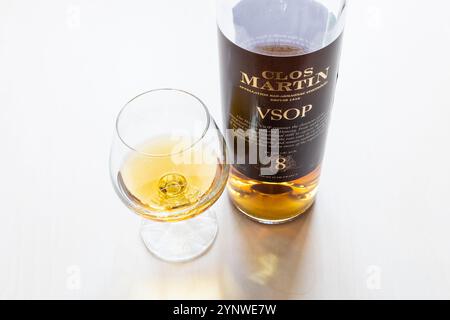 Moscow, Russia - October 1, 2024: wineglass and glass bottle of Clos Martin Bas Armagnac on light brown wooden board Stock Photo