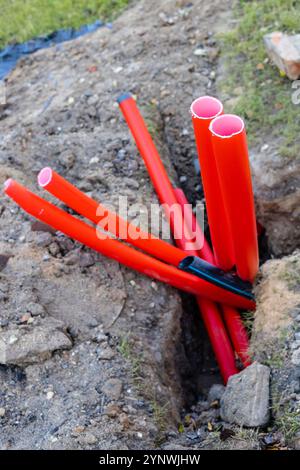 new red plastic conduit pipes for outdoor underground electrical wiring in drain Stock Photo