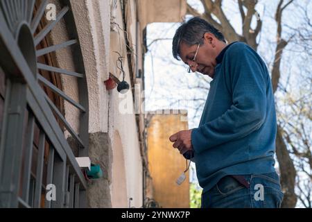 Technician installing photoelectric cell in a house. Stock Photo