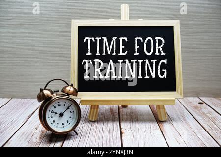 Time For Training text written on chalkboard with alarm clock on wooden background Stock Photo