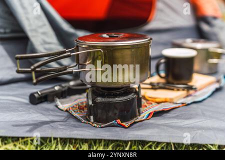camping kitchen items with orange tent background on green grass illuminated with natural light in the andes mountain range Stock Photo