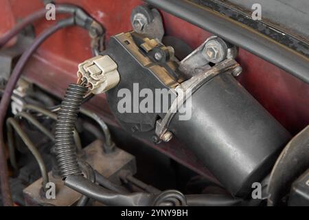 close-up of black windshield wiper motor of car, electric motor with gear mechanism with wiring connected mounted to the engine compartment soft focus Stock Photo