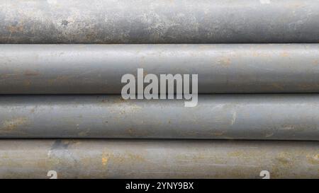 stack of old dirty gray pvc pipes horizontally background texture with worn surface, abstract taken from above with soft focus Stock Photo