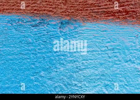 Close-up of an uneven wall spray painted with turquoise or light blue and red. Abstract full frame textured grunge graffiti background with copy space Stock Photo