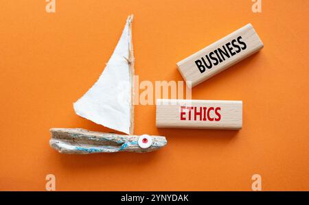 Business ethics symbol. Concept word Business ethics on wooden blocks. Beautiful orange background with boat. Business and Business ethics concept. Co Stock Photo