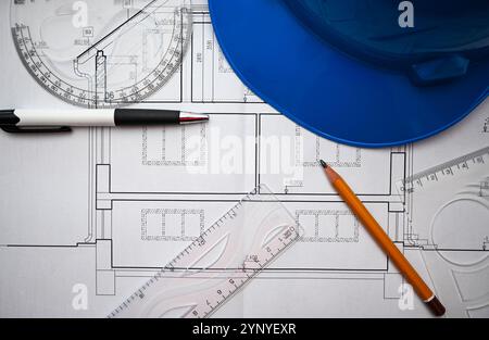 Architectural project planning involves using a blueprint, ruler, protractor, pencil and helmet to ensure accuracy and safety. Stock Photo