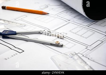 Architectural project with compass, pencil and rolled blueprints lying on construction plans of a house. Stock Photo