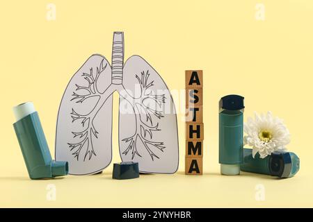 Modern inhalers with word ASTHMA and paper lungs on beige background ...