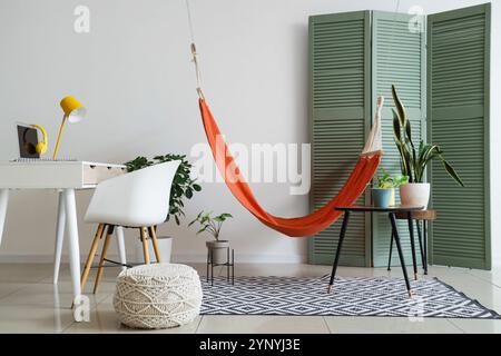 Interior of stylish living room with hanging hammock and modern workspace Stock Photo