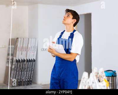 Focused contractor taking notes while planning renovation works in building Stock Photo