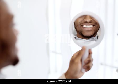 New Smile. Black Man Looking At Mirror While Sitting In Dentist Chair Stock Photo