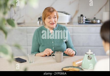 Happy mature woman having conversation in her kitchen with smile Stock Photo