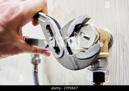 Installing plug on elbow fitting of mixer tap mounting bracket using an adjustable wrench. Stock Photo