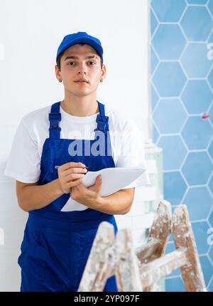 Focused contractor taking notes while planning renovation works in building Stock Photo