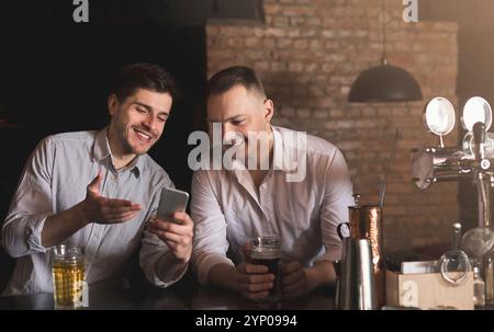 Friends enjoying fresh beer at pub and sharing mobile Stock Photo