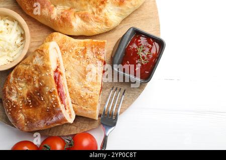 Pieces of fresh calzone pizza served on white wooden table, top view Stock Photo