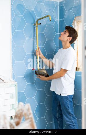 Focused guy assembling shower set before fixing to wall Stock Photo