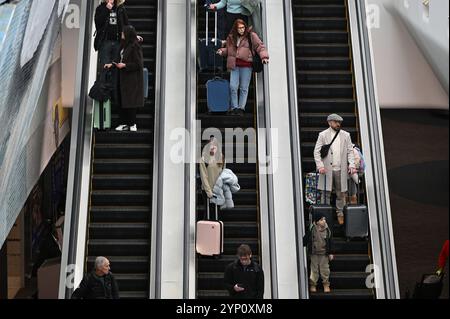 New York, USA. 27th Nov, 2024. Travelers arriving at Terminal B at LaGuardia airport descend an escalator as they arrive in New York on Thanksgiving eve, New York, NY, November 27, 2024. More than 80 million travelers are expected to take the roads, trains and sky, with 6 million expected to fly. (Photo by Anthony Behar/Sipa USA) Credit: Sipa USA/Alamy Live News Stock Photo
