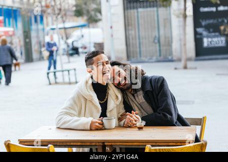 Gay couple laughing and having coffee at outdoor cafe Stock Photo
