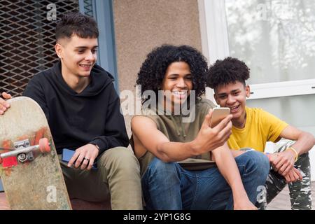 teen friends sharing mobile phone sitting together Stock Photo