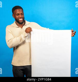 Young black man showing blank white vertical poster on blue background Stock Photo