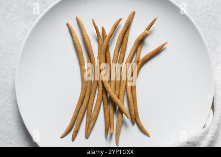 Top view of fried corn stick snack on a white plate, Overhead view of nigerian kokoro corn snack Stock Photo