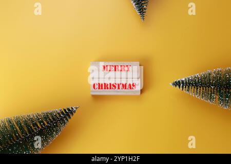 Merry Christmas symbol written on Wooden blocks with words Merry Christmas. Beautiful yellow background. Stock Photo
