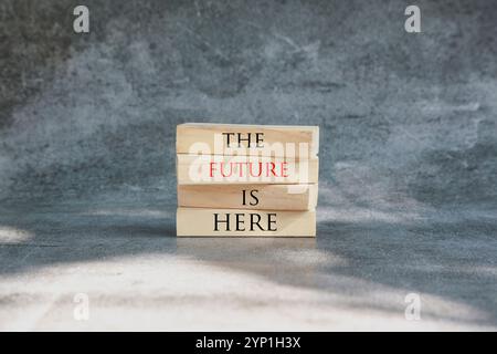 The future is here symbol. Concept words The future is here on wooden blocks. Beautiful grey background. Businessman hand. Business and The future is Stock Photo