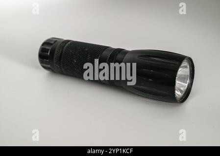 well used small but powerful flashlight or electric torch isolated on white background Stock Photo