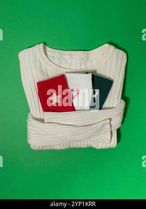 White winter sweater holding colorful socks on a green background Stock Photo