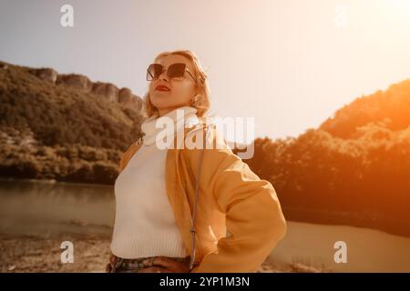 Woman Sunglasses Mountain Landscape - A woman wearing sunglasses stands outdoors in front of a mountainous landscape. Stock Photo