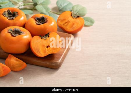 Fresh ripe sweet persimmon kaki fruit on wooden table background. Stock Photo