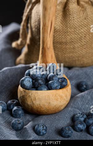 Hand sculpted wooden ladle filled with fresh blueberries on a gray kitchen cloth Stock Photo