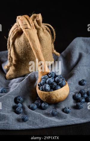 Hand sculpted wooden ladle filled with fresh blueberries on a gray kitchen cloth Stock Photo