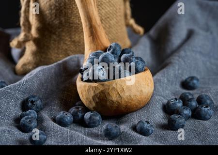 Hand sculpted wooden ladle filled with fresh blueberries on a gray kitchen cloth Stock Photo