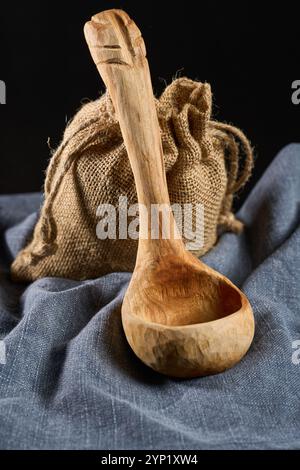 Hand sculpted cherry wood ladle on a gray cloth in closeup Stock Photo