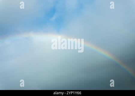 Real photo of a rainbow in the sky with clouds and blue sky Stock Photo