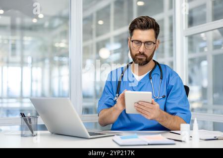 Doctor using tablet and laptop in modern office. Stethoscope around neck, focused on healthcare tasks. Technology in medical practice, optimizing patient care and management. Stock Photo