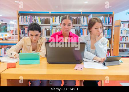 Students using laptops and tablets for study in library Stock Photo