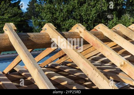 Wooden house roof is under construction. Background photo with rafters and beams, selective soft focus Stock Photo