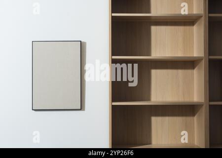 Home interior with empty wooden bookcases and blank framed picture hanging on the wall Stock Photo