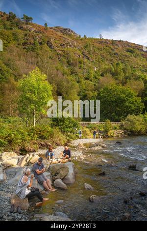 UK, Wales, Gwynedd, Snowdonia, Beddgelert, Aberglaslyn, visitors beside Afon Glaslyn flowing over rocks through pass Stock Photo