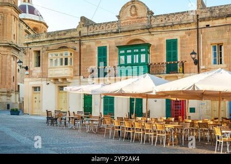 Street restaurants and cafes on the town square by the Parish Church in the popular fishing village of Marsaxlokk, Malta Stock Photo