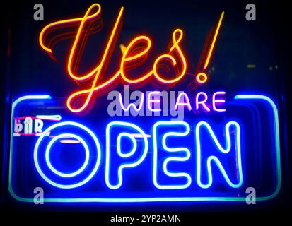 Yes, we're open - glowing neon sign board on glass window during night time Stock Photo