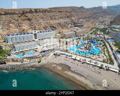 A stunning aerial perspective of Gran Canaria’s cliffside resorts featuring luxurious accommodations, a vibrant waterpark, and a sandy beach along the Stock Photo